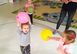 Zdjęcie dzieci bawiących się kolorowymi balonami.