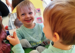 Uśmiechnięty chłopiec przegląda się w okrągłym lustrze.