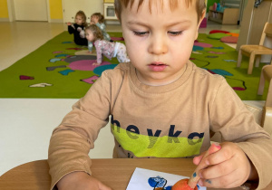 Chłopczyk podczas malowania szablonu stworka.