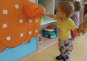 Stanisław przykleja na szablon dyni pierwsze pomarańczowe baloniki.