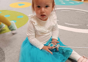 Zdjęcie Laury siedzącej na dywanie w przebraniu księżniczki.