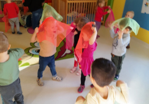 Dzieci naśladują wiatr machając chustami.