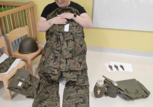 Opiekunka pokazuje dzieciom mundur żołnierza.