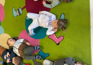 Zdjęcie dzieci leżących na dywanie podczas zabawy relaksacyjnej.
