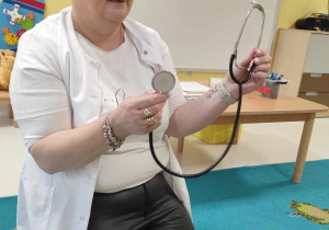 Opiekunka pokazuje dzieciom stetoskop.