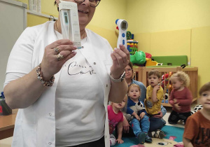 Opiekunka pokazuje dzieciom dwa rodzaje termometrów.