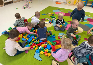 Dzieci bawiące się na dywanie klockami.
