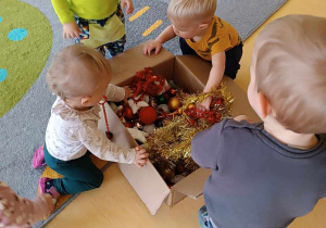 Zdjęcie dzieci wyciągających dekoracje świąteczne z ogromnego tekturowego pudła.