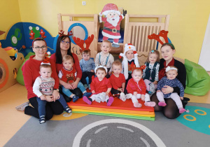 Pamiątkowe zdjęcie dzieci i opiekunek z grupy Motylki wykonane w dniu odwiedzin Świętego Mikołaja i Mikołajki.