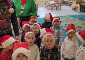 Dzieci i opiekunki z grupy Pszczółki ustawione w parach, szykują się do przejścia do grupy Biedroneczek na spotkanie ze Świętym Mikołajem i Mikołajką.