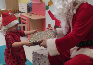 Mikołaj wręcza Laurze prezent.