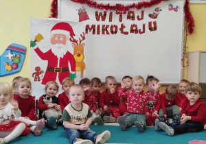 Pamiątkowe zdjęcie dzieci wykonane w Mikołajki, na tle ścianki wykonanej przez opiekunki.