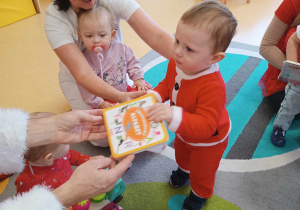 Mikołaj dostaje od Mikołaja pomarańczowo - białą książeczkę.