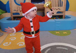 Mikołaj bawi się złotym dzwoneczkiem Świętego Mikołaja.