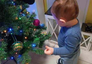 Zdjęcie Mikołaja podczas dekorowania na korytarzu świątecznego drzewka.