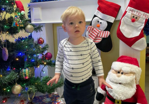 Zdjęcie chłopca na tle choinki i świątecznego kominka.