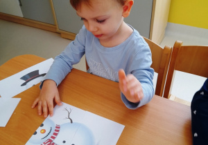 Chłopiec układa obrazek przedstawiający bałwanka.