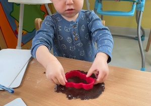 Zdjęcie małego chłopczyka wykrawającego ciasteczko w kształcie bałwanka.