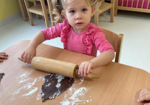 Mała dziewczynka wałkuje ciasto na pierniki.