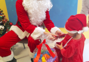Dziewczynka odbiera prezent od Świętego Mikołaja.