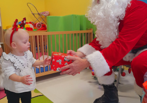 Mikołaj wręcza podarunek małej dziewczynce.