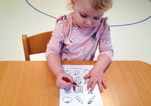 Dziewczynka maluje kredką szablon klocków.
