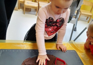 Dziewczynka podczas wykrawania bałwanka z piernikowego ciasta.