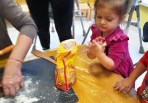 Dziewczynka otrzepuje rączki z mąki.