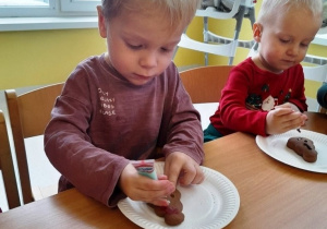 Chłopiec dekoruje kolorowym pisakiem pierniczek.