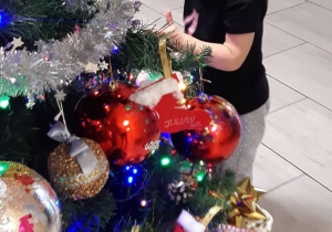 Dziewczynka przystraja świąteczne drzewko.