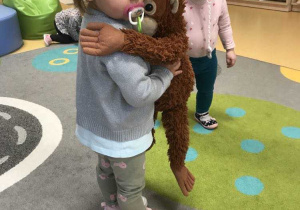 Zdjęcie Laury przytulającej brązową zabawkową małpkę.
