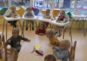 Zdjęcie dzieci z grupy Motylki siedzących przy stoliczku i przygotowujących się do zajęć plastycznych pt. ,,Kolorowa zakładka do książki''.
