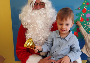 Chłopiec pozuje do zdjęcia na kolanach u Świętego Mikołaja.