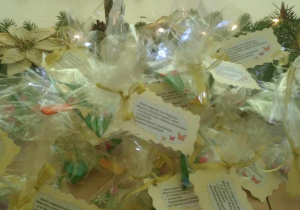 Zdjęcie przygotowanych dla dzieci przez opiekunki z grupy Motylki upominków, w postaci przepięknych świątecznych choineczek zapakowanych w celafon i przyczepioną karteczką z Bożonarodzeniowymi życzeniami.