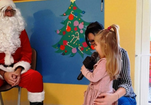 Zdjęcie dziewczynki mówiącej do mikrofonu wiersz dla Świętego Mikołaja.