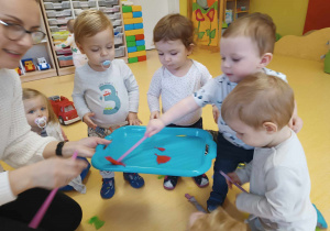 Zdjęcie dzieci podczas zajęć z kolorowymi piórkami i słomkami.