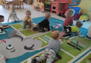 Dzieci kładą się na dywanie naśladując przy tym wyświetlanego na tablicy interaktywnej topniejącego bałwanka.