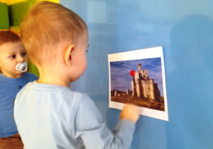 Chłopczyk przykleja do tablicy obrazek z zamkiem.