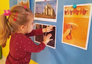 Dziewczynka przykleja do tablicy obrazek z zamkiem błyskawicznym.