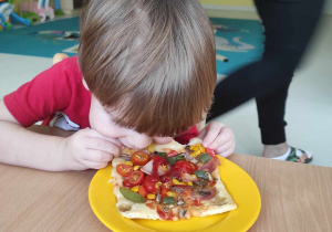 Zdjęcie Miłosza podczas jedzenia swojego kawałka pizzy.