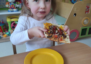 Lilianna pozuje do zdjęcia trzymając w dłoni swoją pizzę.