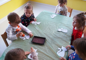 Dzieci siedzące przy stole podczas wykonywania pracy plastycznej.