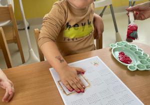 Chłopiec pozuje do zdjęcia podczas odbijania dłoni na kalendarzu z okazji święta Babci i Dziadka.