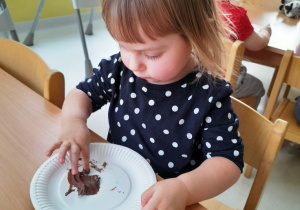 Dziewczynka macza pluszki w czekoladowym kremie.