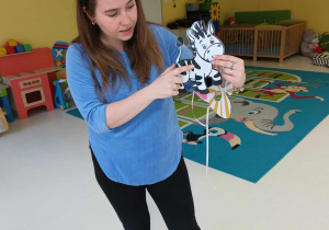 Opiekunka pokazuje dzieciom na wydrukowanym i zalaminowanym szablonie w jakich barwach jest zebra.
