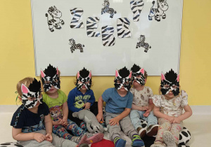 Pamiątkowa fotografia dzieci z założonymi na twarzach własnoręcznie wykonanymi maskami przedstawiającymi zebry.