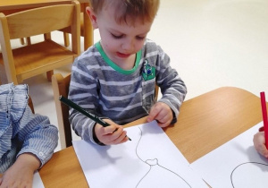 Chłopiec maluje szablon balonika na zielono.