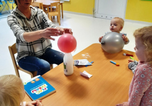 Opiekunka podtrzymuje balon, który pompowany jest przez połączenie sody z octem.