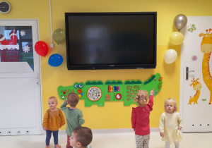 Zdjęcie dzieci przyglądających się balonikom na ścianie.