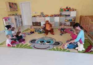 Zdjęcie Misia z dziećmi siedzącymi na dywanie.